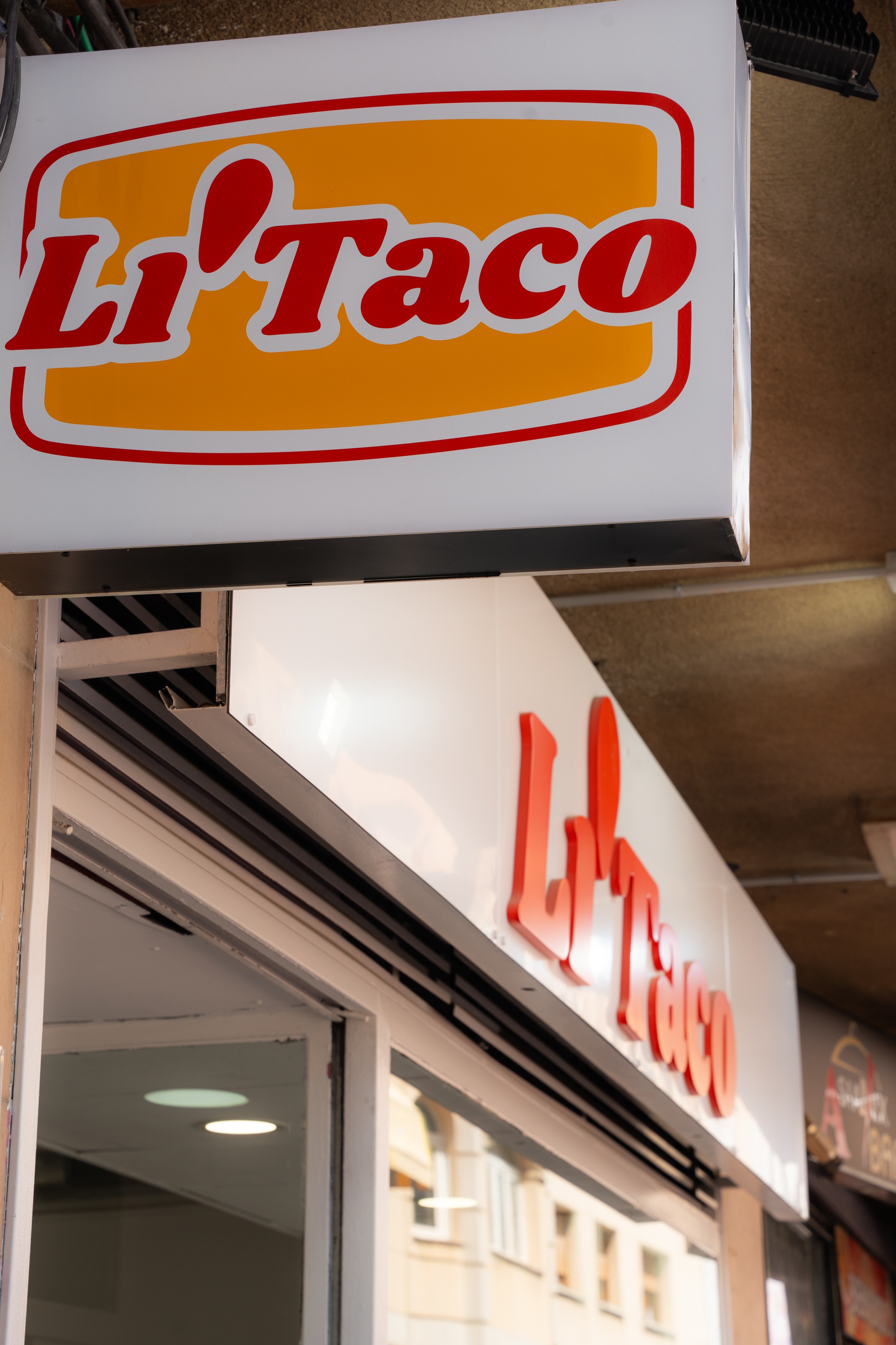 Fachada del local de LiTaco en Getafe, con el rótulo luminoso y las letras rojas sobre el escaparate